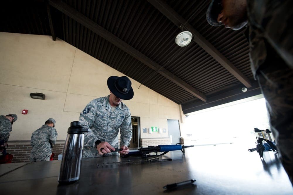 Air Force BMT trainees firing M4 rifles during weapons qualification at the firing range