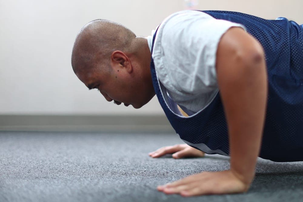 Airman performing push-ups during a fitness assessment while a proctor counts