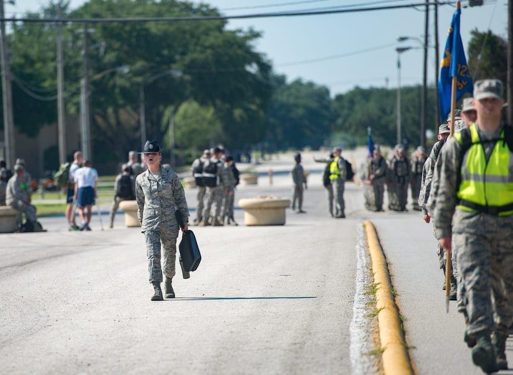 Military Training Instructor in blue campaign hat leading trainees during drill formation at JBSA-Lackland
